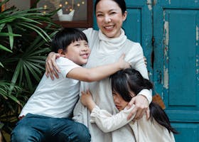 Photo of Woman Hugging Her Children While Smiling